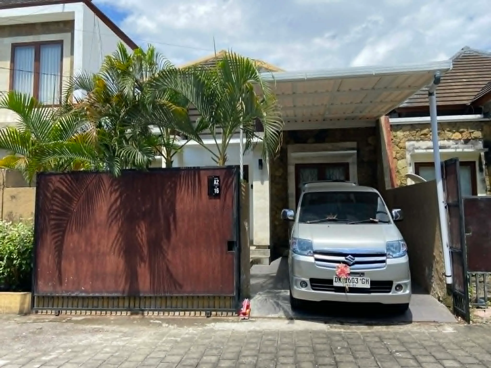 Koláž pěti fotografií z pronajatého domku v rezidenci Royal Garden na Nusa Dua, Bali. Zobrazuje sdílený bazén s lehátky, vjezd s autem a čistý interiér obývacího pokoje a dvou ložnic.