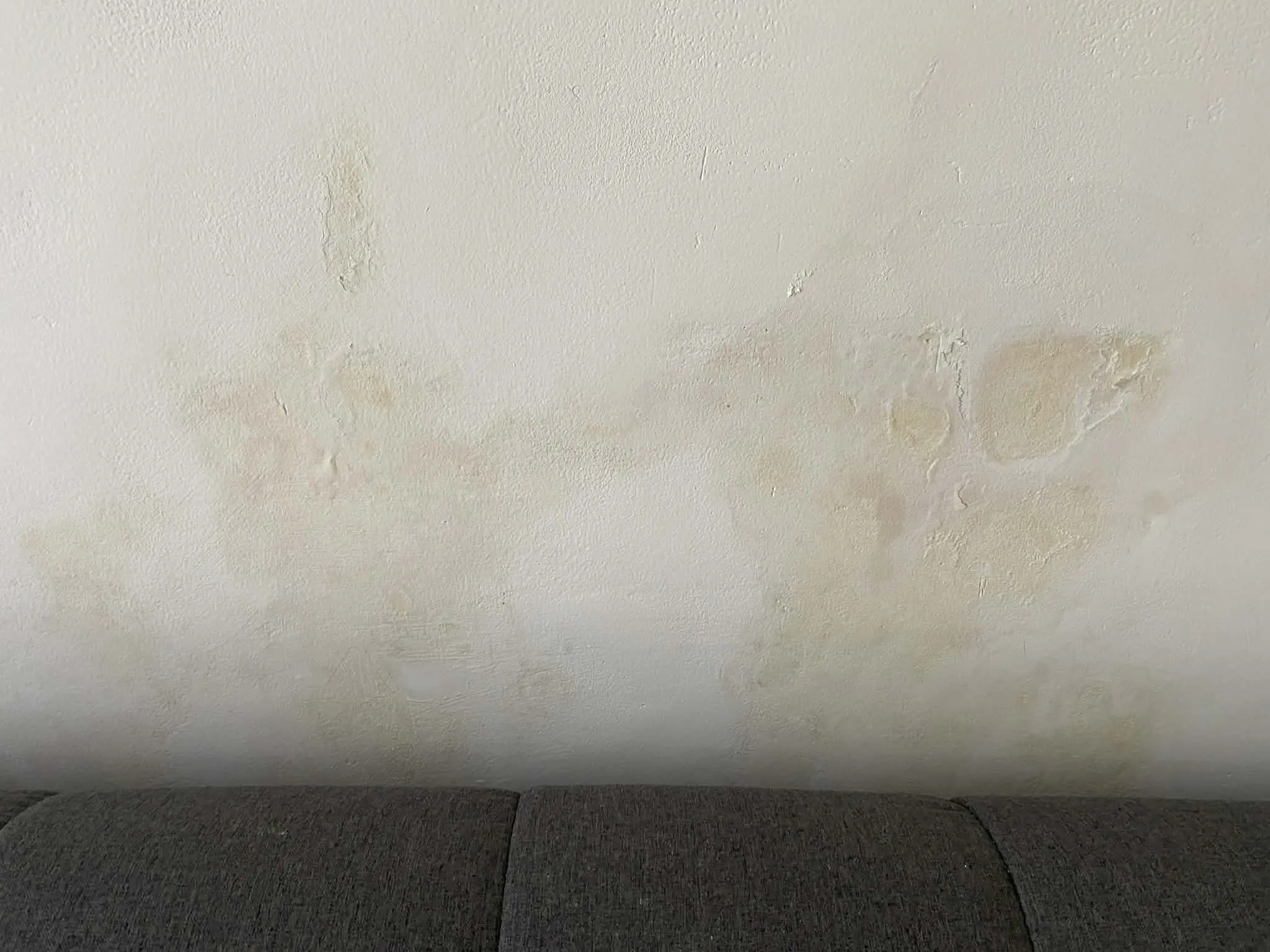 Detailní fotografie silné plísně na zdi uvnitř pronajímaného domu na Bali. Ukázka problému s vlhkostí a nekvalitní stavbou.