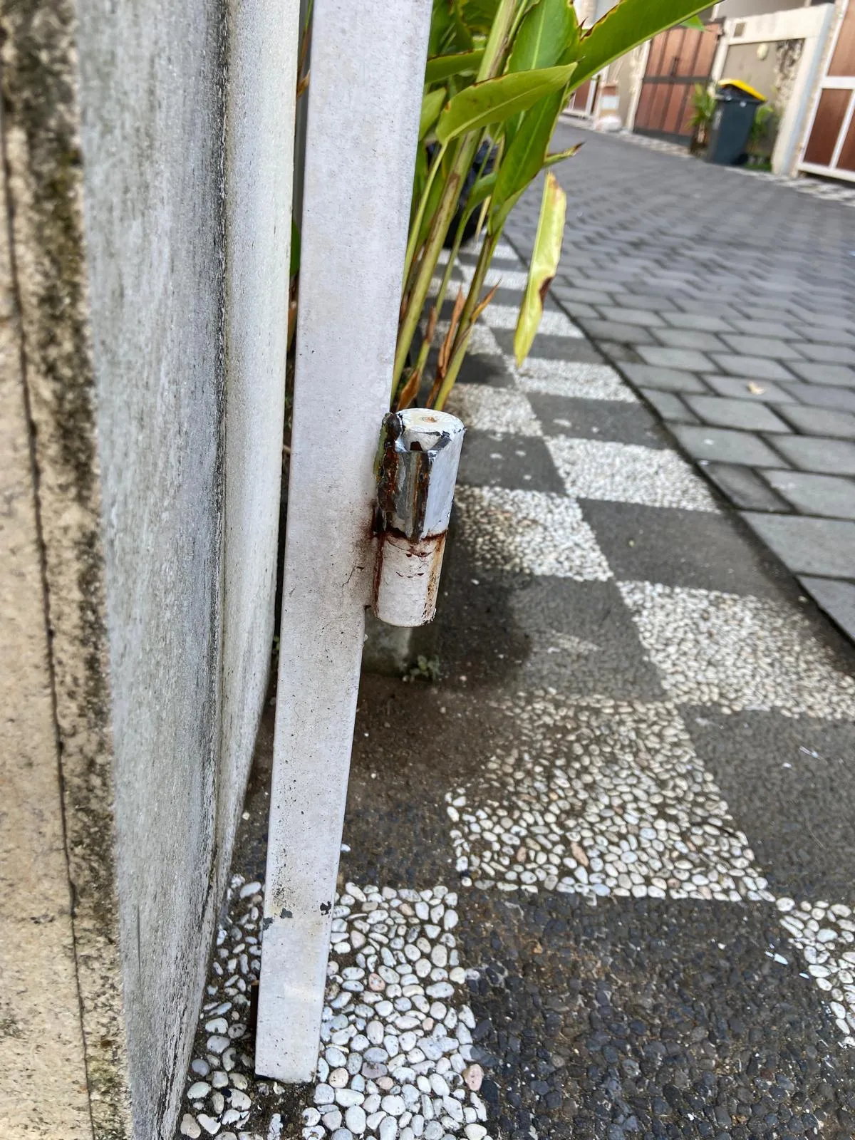 Urvaný a zrezlý pant rozkládací brány u domu na Bali