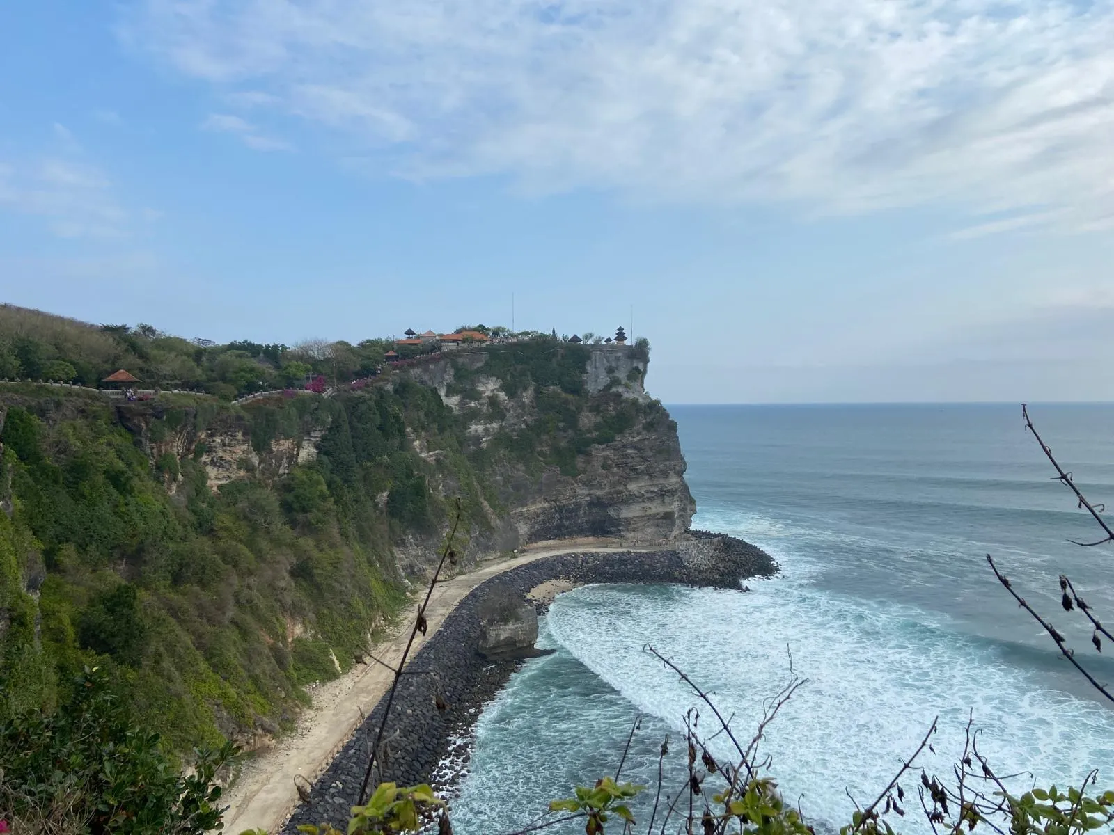 Vápencové útesy Uluwatu na jihu Bali, na jejich hraně chrámový areál Pura Luhur Uluwatu a pod nimi tyrkysový oceán s příbojem