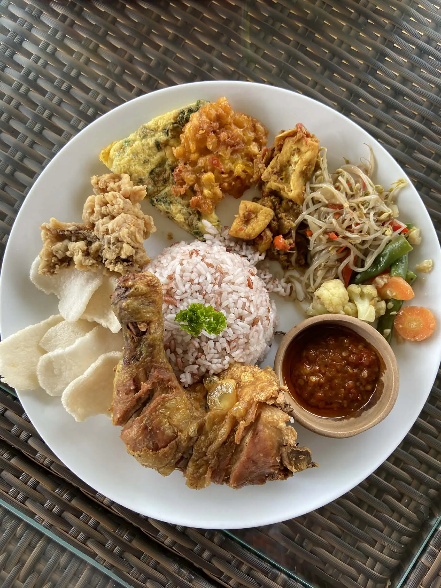 Tradiční balijské jídlo Nasi Campur – rýže, tempeh, tofu, kuře a pikantní sambal omáčka v lokální restauraci v Jatiluwih.